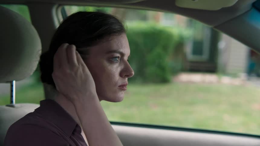 A woman looks at a cell phone while sitting in a car