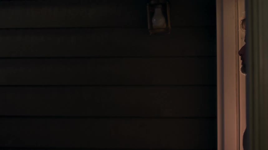 A man opening a sliding door and standing in the doorway of his porch