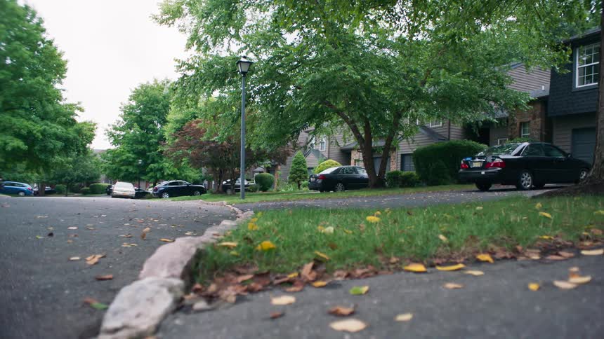 A sedan drives down a residential street
