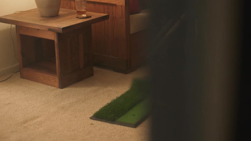 A man golfs in his living room