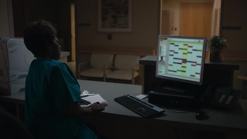 A woman at the front desk of an office goes and consoles a woman in the waiting room that is crying