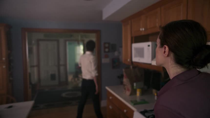 A man walks away from a woman in a house