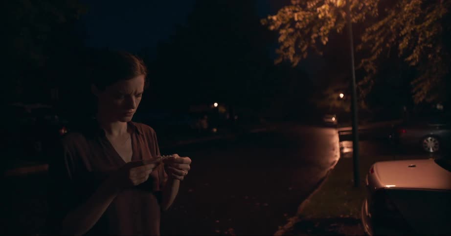 Woman looks down on a piece of paper and moves forwards at night