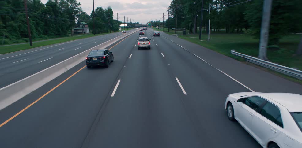 Cars travel on a three lane highway passing cars going in the opposite direction