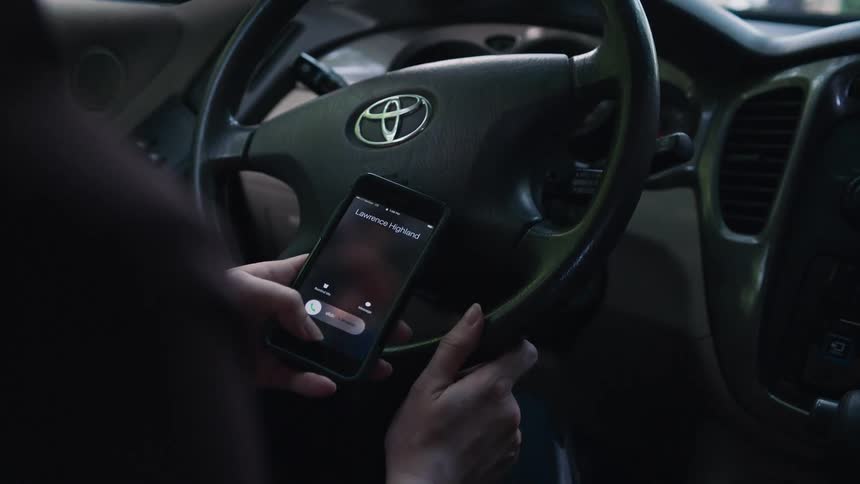A woman inside a car looking at her smart phone