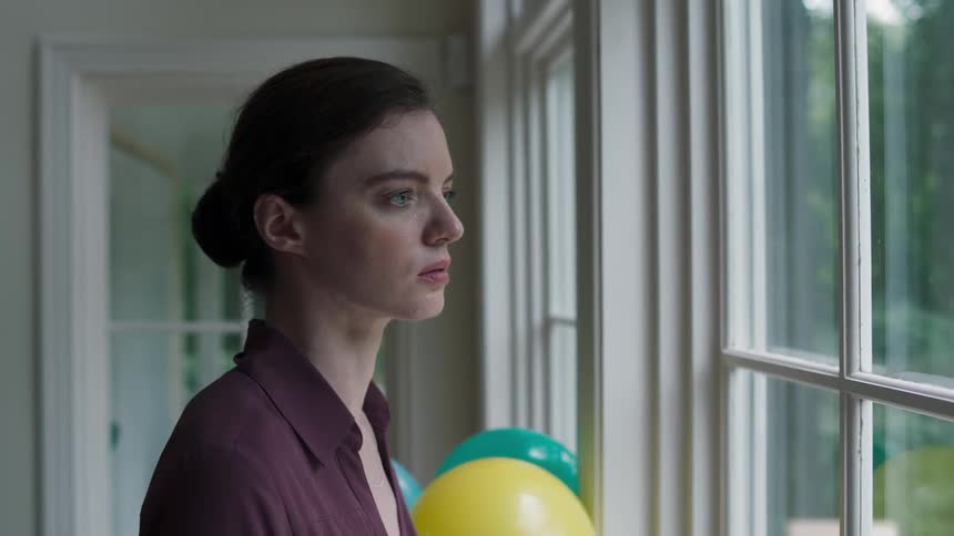 A woman swallows nervously as she looks out the window