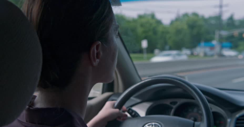 A woman flips on her directional signal while driving on a multi lane highway