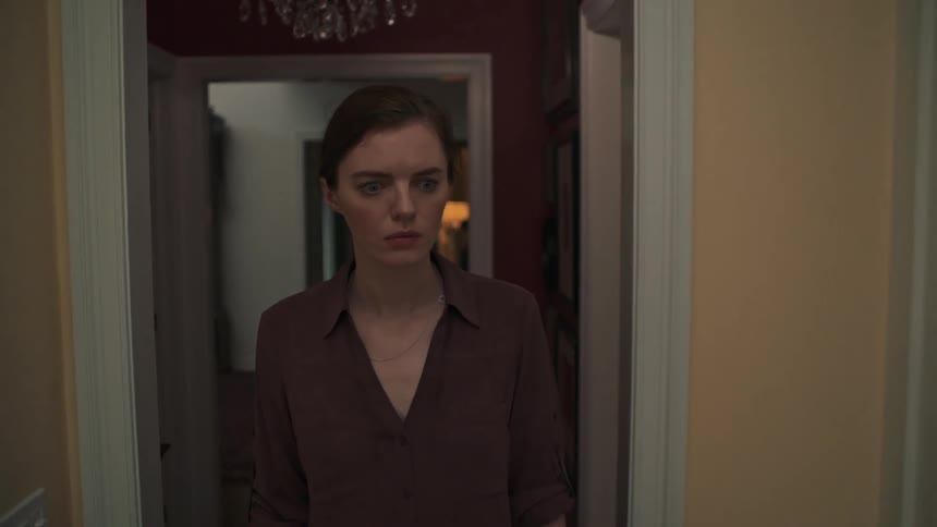 A woman enters a home and closes the door behind her before walking cautiously through the house