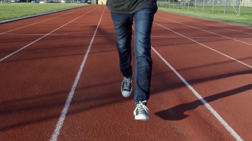 A person jogs outside on a racetrack