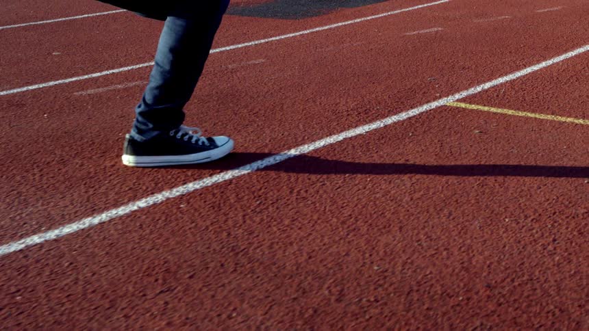 A runner's shadow is cast on a racing track