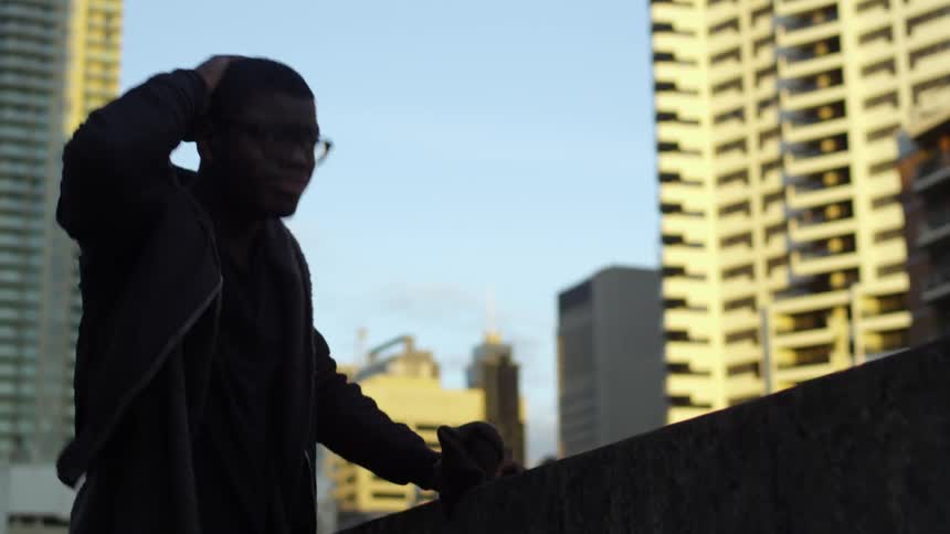 A man looks upset while standing on the roof of a building during the day