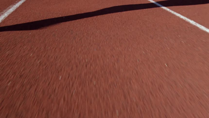 A runner's shadow is cast on a racing track