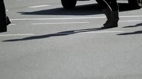 Some people walk across asphalt