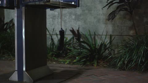A payphone dangles by its cord