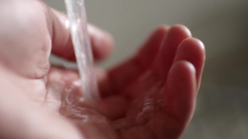 A hand lingers under running water