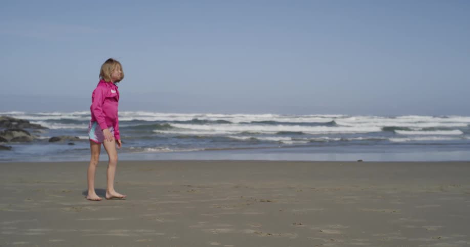 A girl does cartwheels on the beach during the day