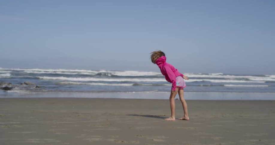 A child does a cartwheel on the beach
