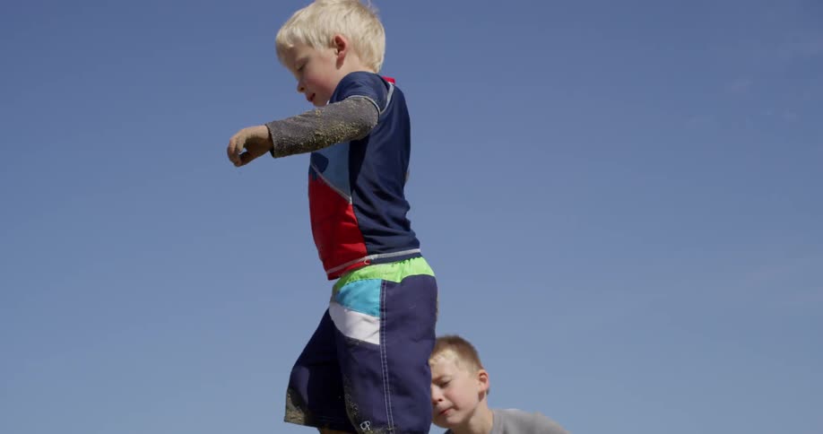 Boys climb and play on a pile of sand