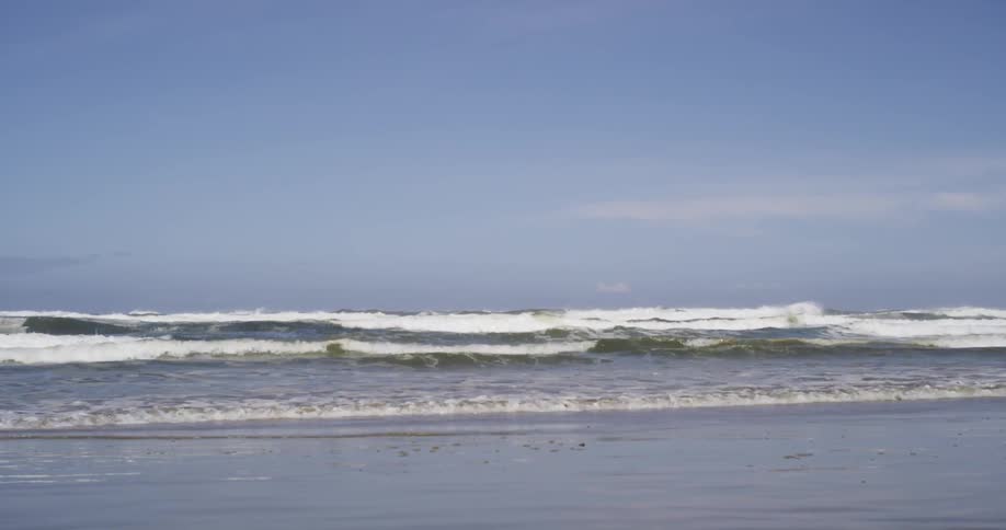 A man runs on the beach then slides on a surfboard
