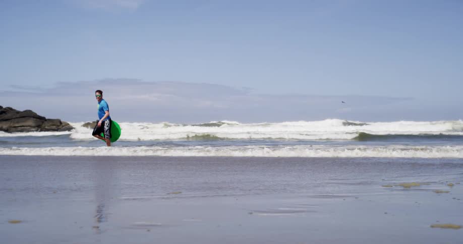 A man walks in ocean waves on a sunny day