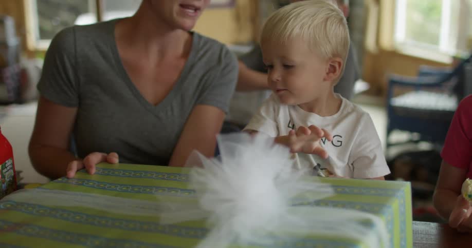 A woman hands a large present to a small child