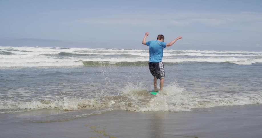 A man uses a boogie board on the beach