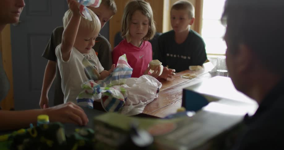 A group of people are sitting at a table one is opening presents