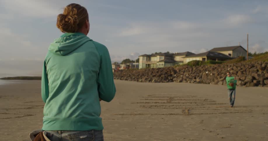 Two people are throwing a baseball back and forth on a beach