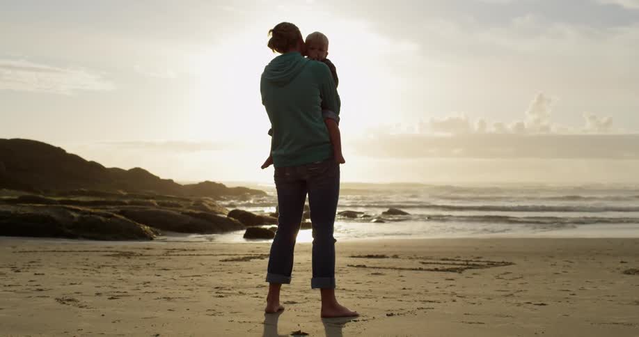 Woman standing and cuddling baby on the beach