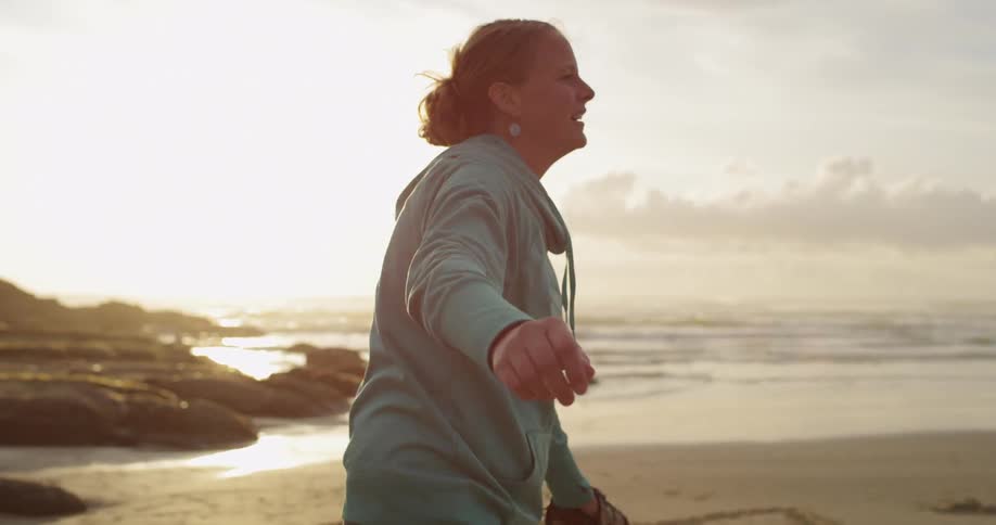 A woman in a blue hoodie throws a baseball