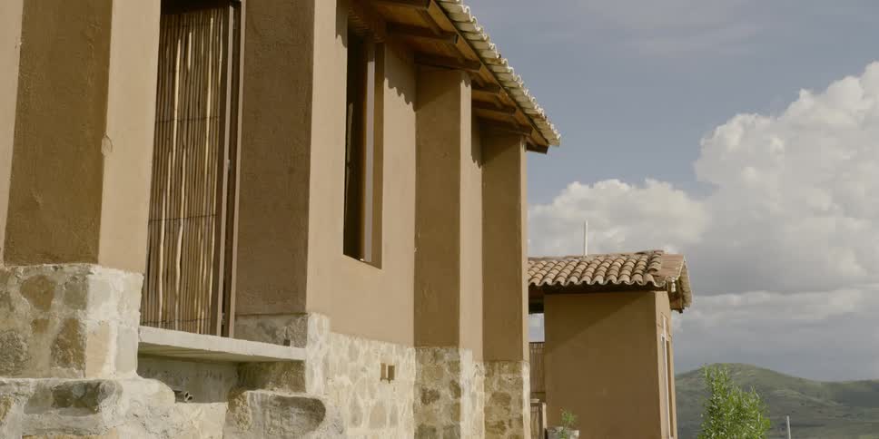Woman turns and walks inside from porch of adobe house