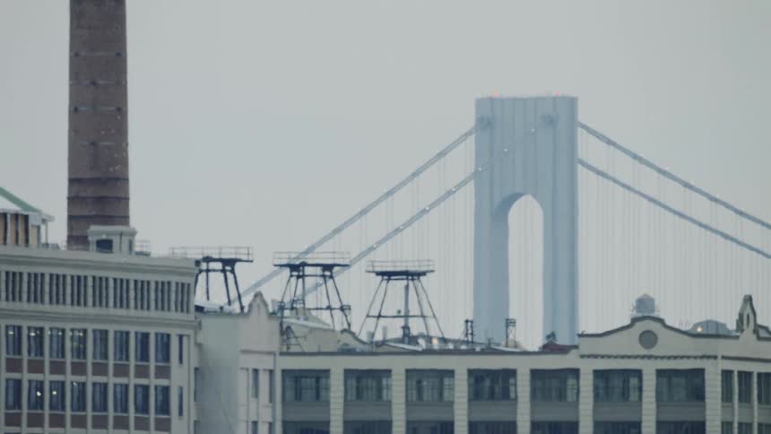 A bridge and cables are visible over rooftops on a rainy gray day