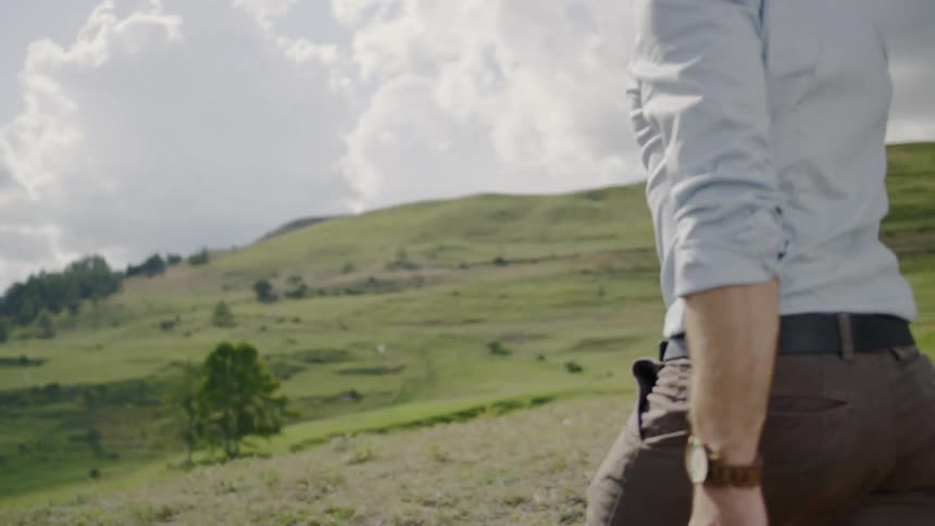 A white man walks across grassland