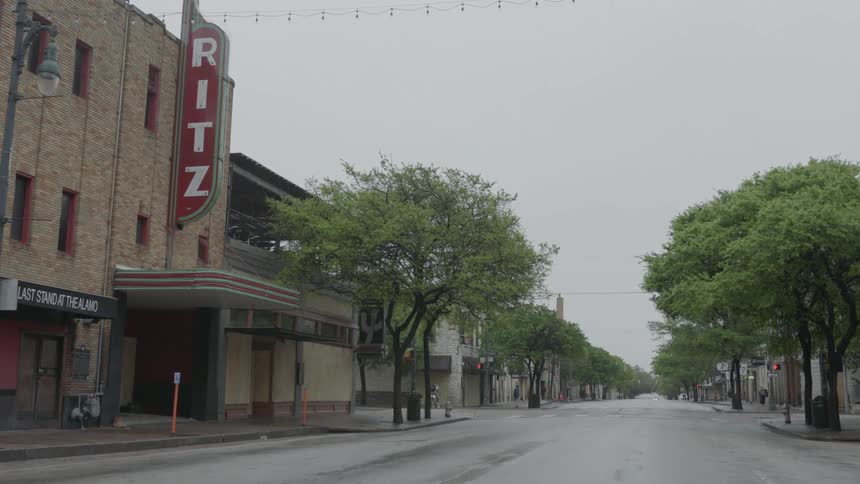 The empty streets of a towns downtown area with only a few people on the sidewalks