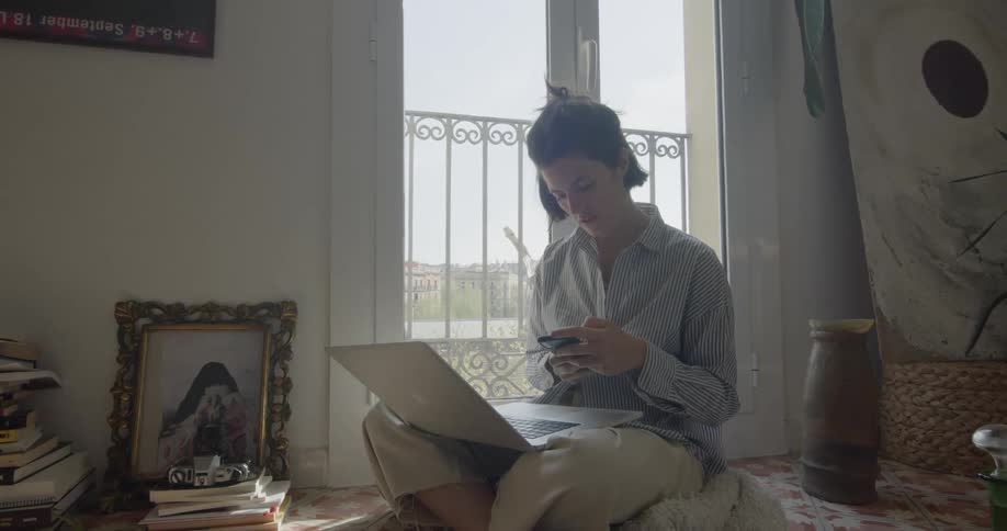 Woman sitting cross legged uses a smartphone in the living room