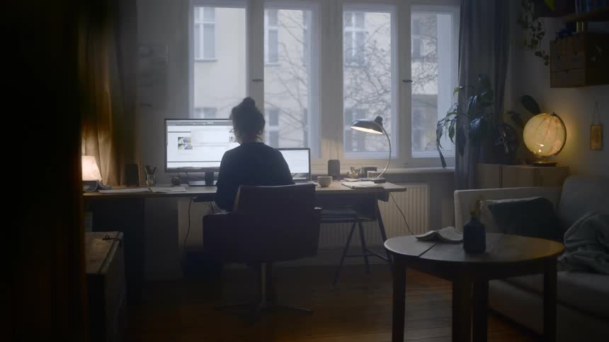 A woman sits at her desk and scrolls through a site on her computer
