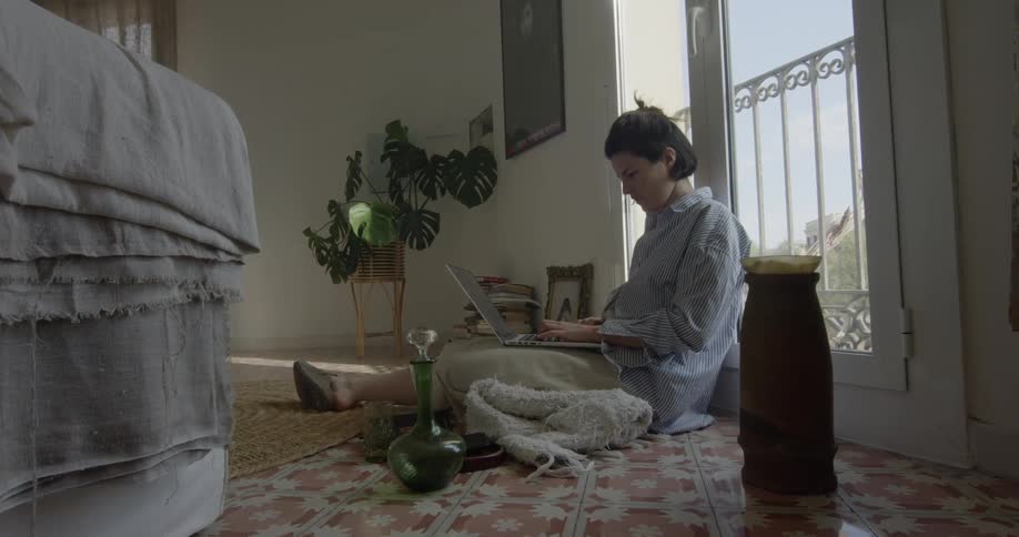 A person is sitting in a room and typing on a laptop