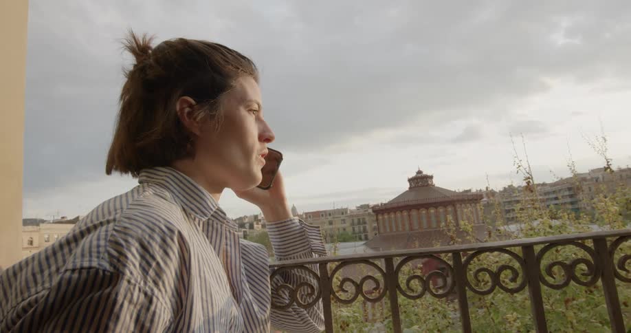 Man talks to someone on the smart phone in the balcony of the apartment at sunset