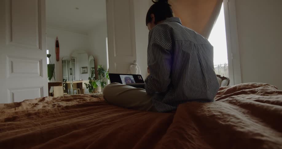 Man sits on bed talking to woman on video chat