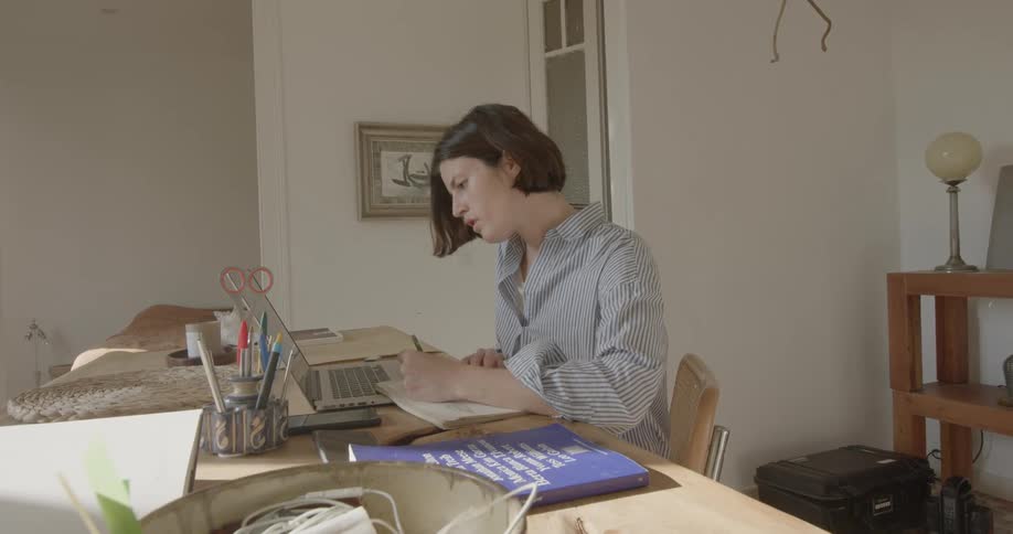 Woman works at desk at home taking notes