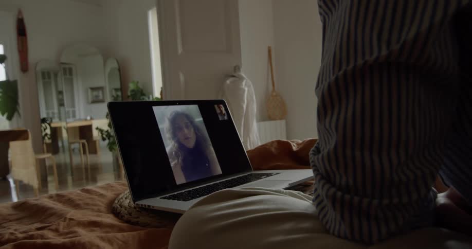 A man sitting and video chatting with a woman on a laptop