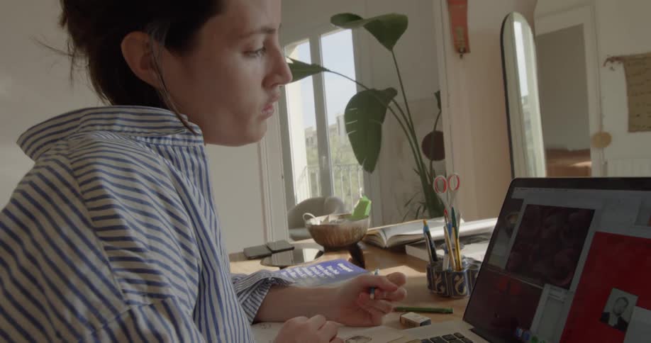 A teenager looks at her laptop while drawing