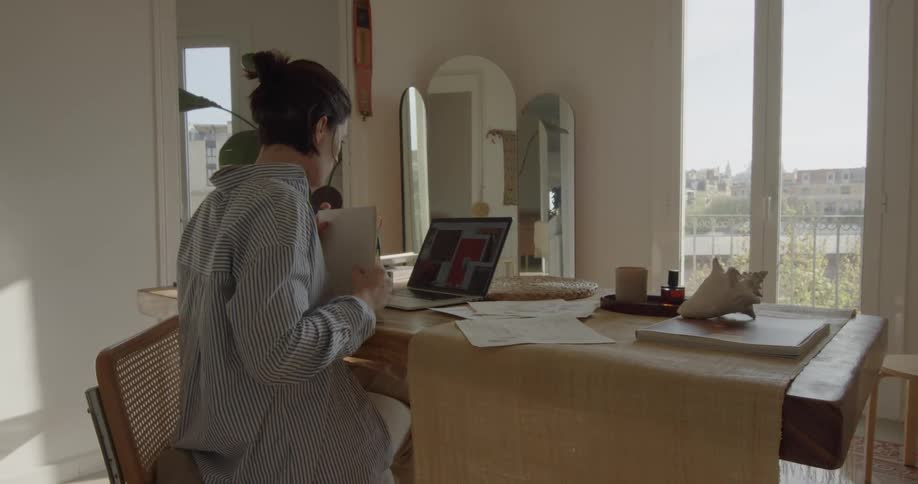 A woman goes through paperwork while sitting at her desk in front of a laptop