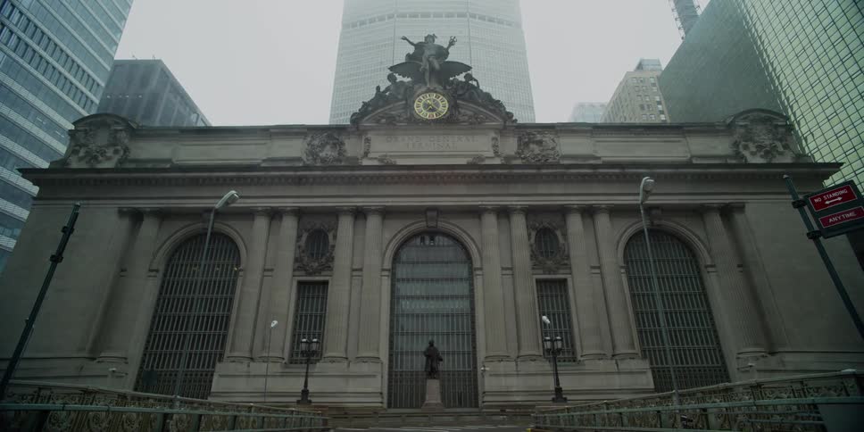 A building with a statue in front and skyscrapers in the background