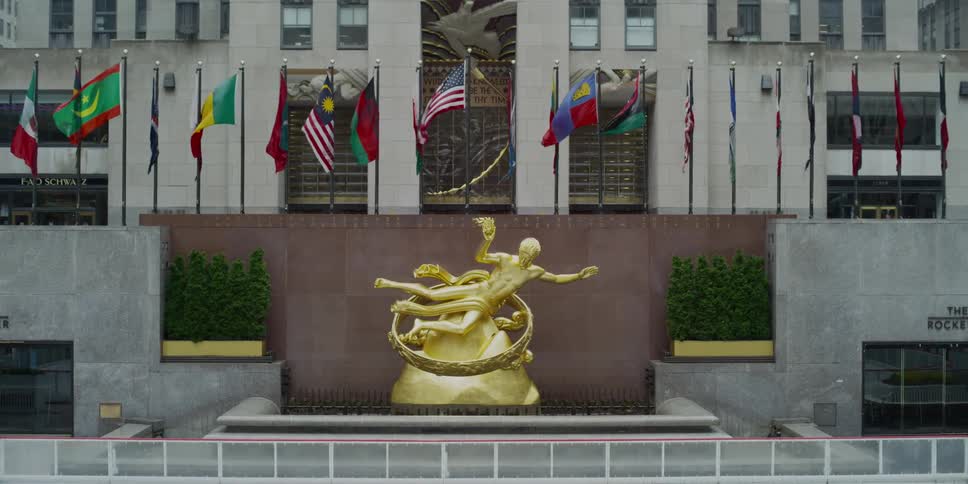 A statue in front of a building surrounded by flags
