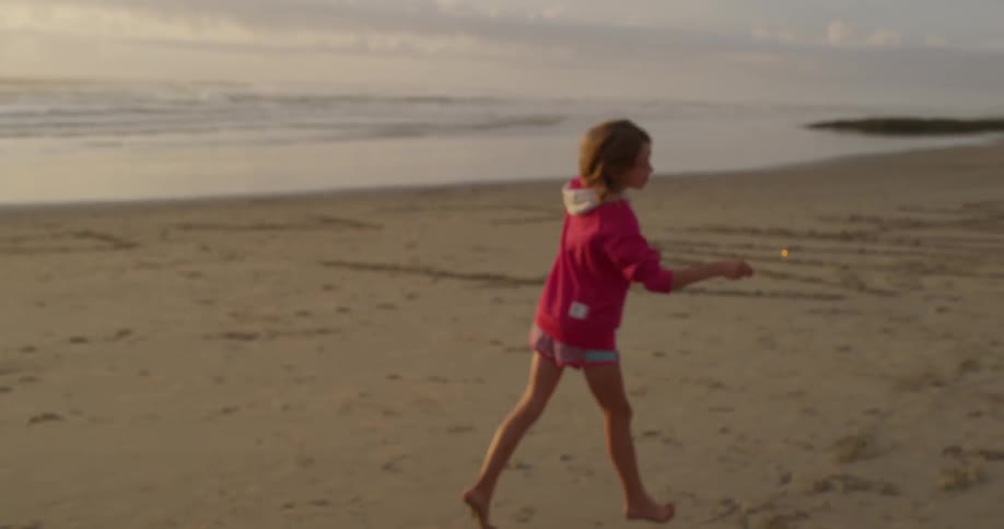 A child is running around with a sparkler on the beach