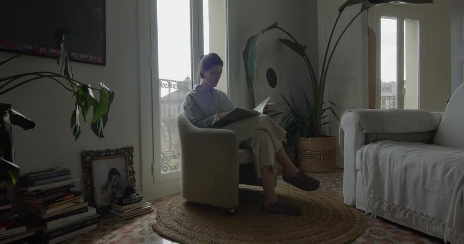 Man sitting in a chair leaves through magazines at home