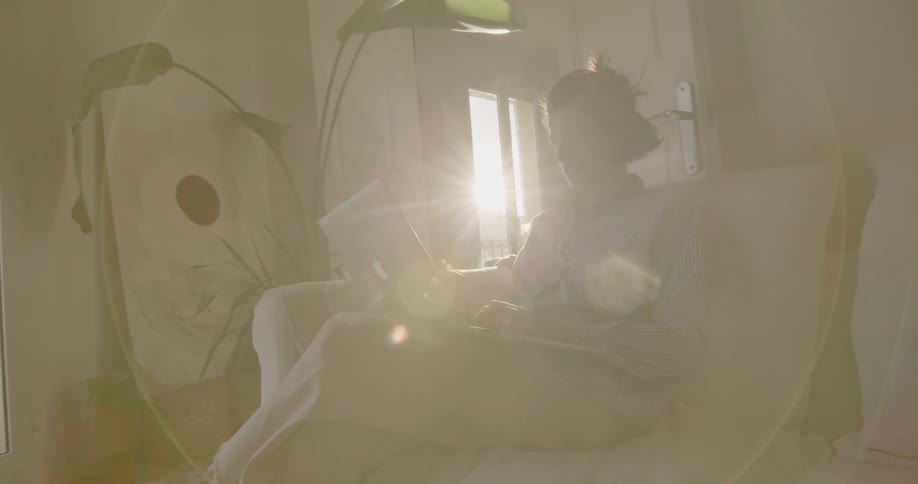 Man sitting on the couch uses a laptop in the living room at sunset