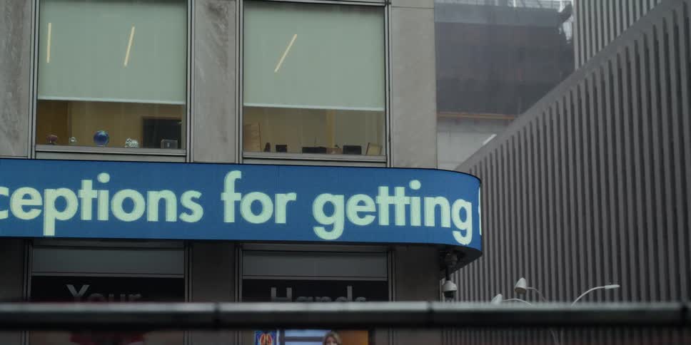 A sign warning people to stay home scrolls on a building