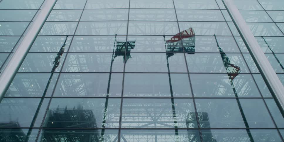 Flying flags reflected in the glass facade of a large building